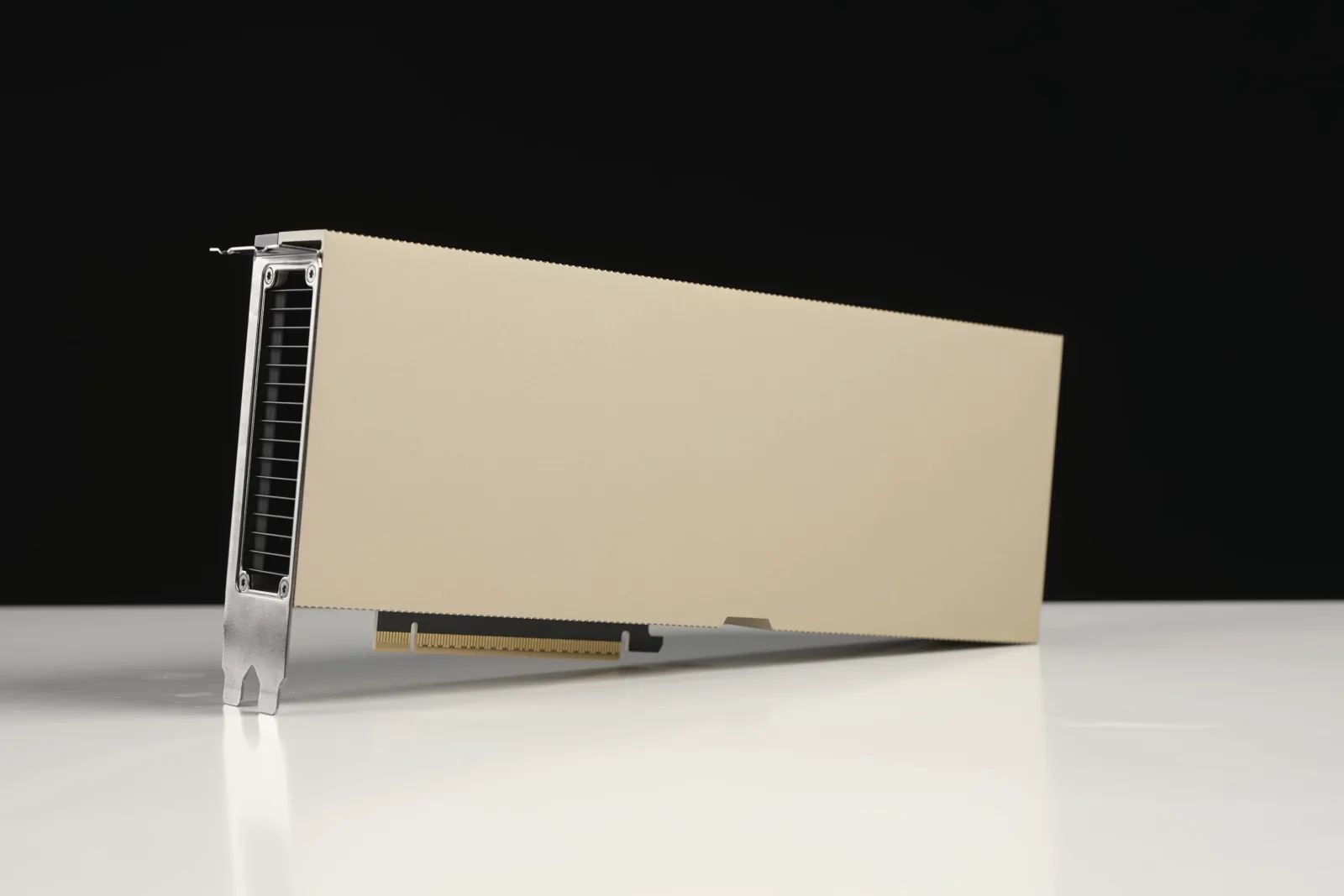 A long, gold-colored GPU card with a perforated metal bracket at one end stands on its edge on a white surface against a black background.